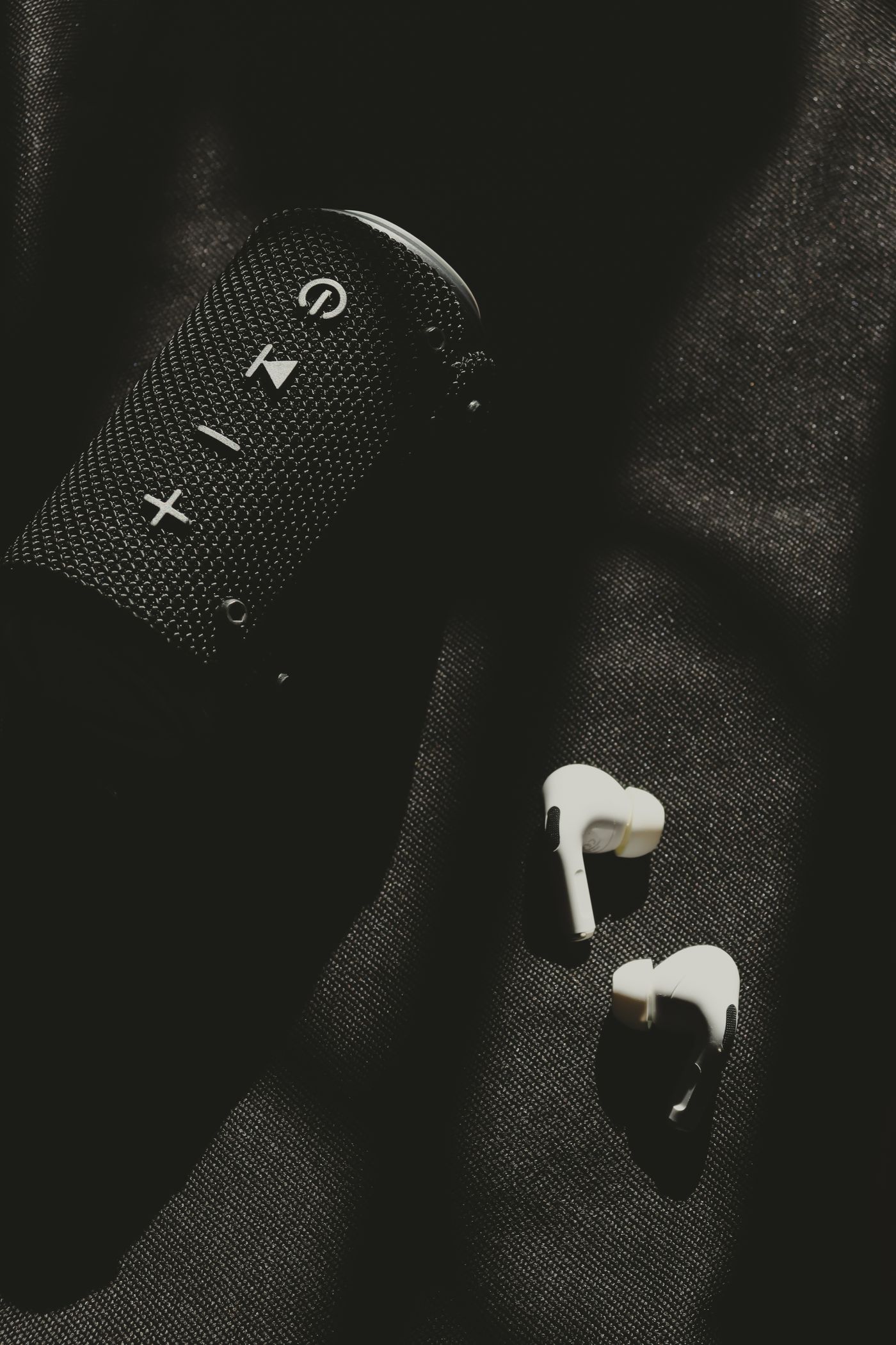 Wireless earphones beside a portable speaker